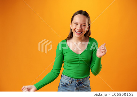 Portrait of a joyful happy teenage girl celebrating success on yellow background Portrait of a joyful happy teenage girl celebrating success on yellow background 106860155