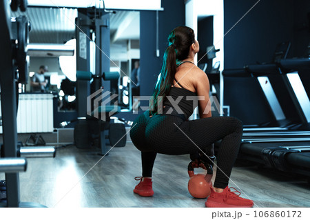 Athletic woman exercising with kettle bell in a gym 106860172