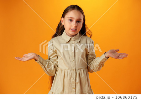 Teen girl shows I don't know gesture against yellow background Teen girl shows I don't know gesture against yellow background 106860175