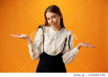 Teen girl shows I don't know gesture against yellow background Teen girl shows I don't know gesture against yellow background 106860196