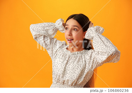 Surprised teenage girl over yellow background in studio Surprised teenage girl over yellow background in studio 106860236