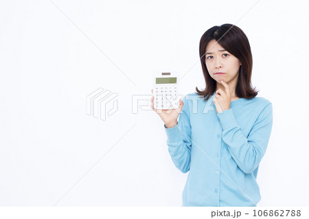 白い背景の前で電卓を持ち悩んでいる30代の主婦 白い背景の前で電卓を持ち悩んでいる30代の主婦 106862788