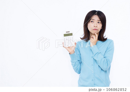 白い背景の前で電卓を持ち悩んでいる30代の主婦 白い背景の前で電卓を持ち悩んでいる30代の主婦 106862852