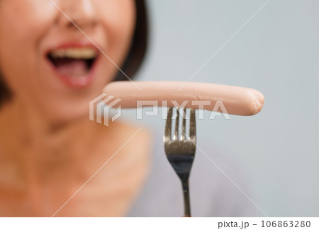 魚肉ソーセージを食べる笑顔の女性　顔無し 106863280