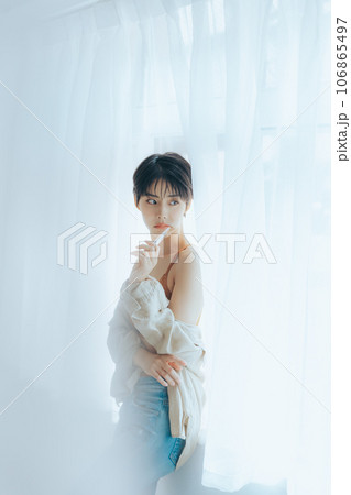 朝日を浴びて外を眺める女性 106865497