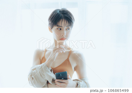 朝日を浴びて外を眺める女性 106865499