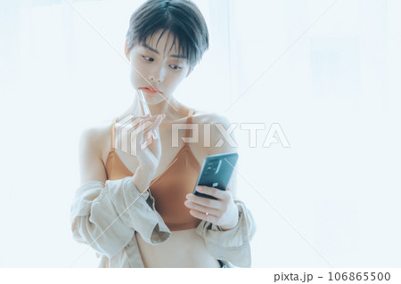 朝日を浴びて外を眺める女性 106865500