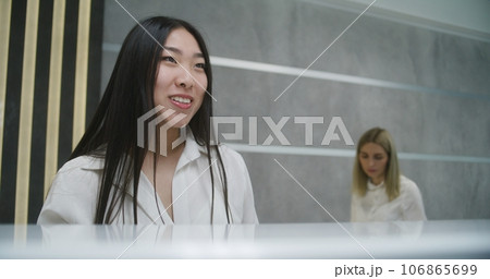Asian female administrator talks with patient on reception Asian female administrator talks with patient on reception 106865699