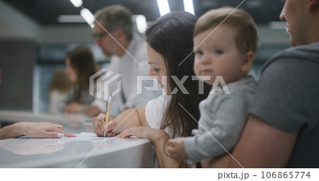 Caucasian family with child stand at reception desk in clinic Caucasian family with child stand at reception desk in clinic 106865774