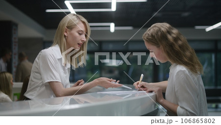 Female administrator consults person, helps fill out papers in hospital 106865802