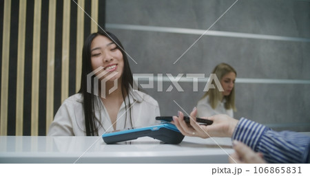Woman pays for appointment with doctor in clinic using phone Woman pays for appointment with doctor in clinic using phone 106865831