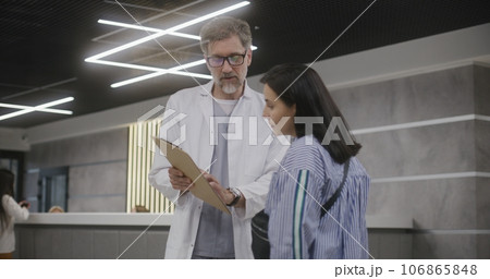 Adult woman stands with doctor in clinic lobby near reception 106865848