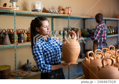 Two positive smiling potters in the process of work at the workshop 106867026