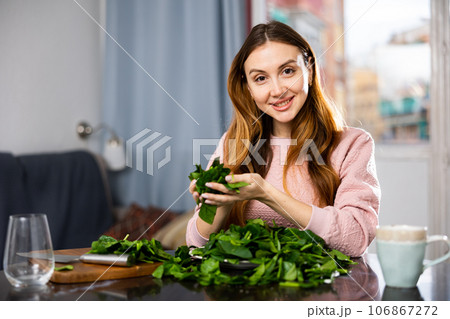 Happy girl making delicious spinach salad closeup Happy girl making delicious spinach salad closeup 106867272