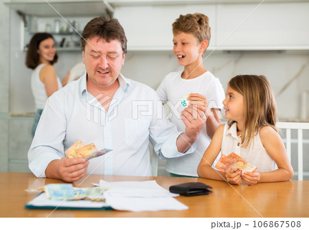 Happy father giving money to children in the kitchen 106867508