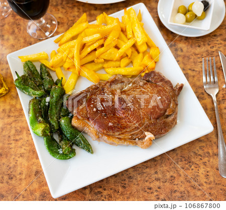 Serving of grilled beef with potatoes and spicy pepper on side 106867800