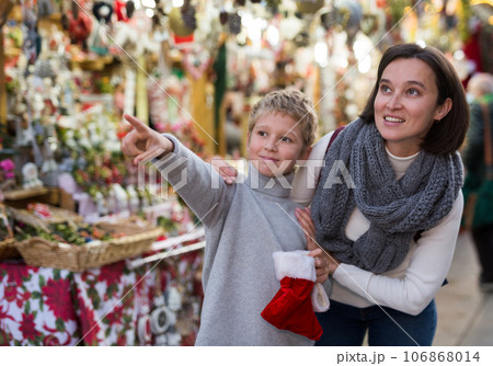 Tween boy with mother choosing Xmas decorations on street fair 106868014