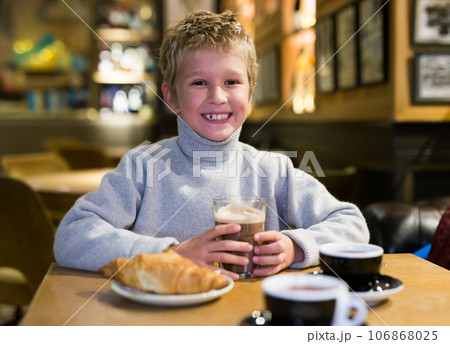Happy preteen boy enjoying hot chocolate with croissant in cafe Happy preteen boy enjoying hot chocolate with croissant in cafe 106868025
