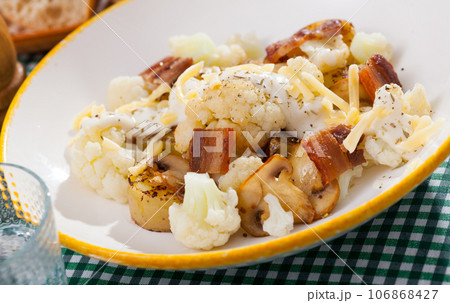 Baked potatoes with cauliflower, bacon, cheese sauce 106868427