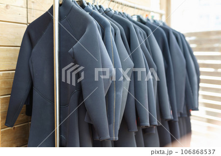 Black surfing wetsuits hanging on rack for rent in surf club Black surfing wetsuits hanging on rack for rent in surf club 106868537