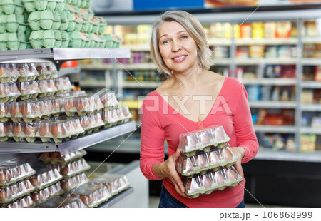 Mature woman choosing fresh eggs in grocery shop 106868999