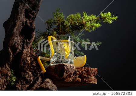 Cocktail gin-tonic with lemon in a crystal glass on an old board. 106872802