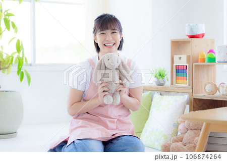 保育士ポートレート　ぬいぐるみを持ちカメラ目線で微笑む保育士 106874264