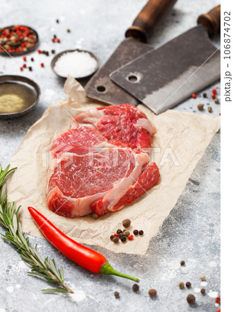 Red raw beef rib eye steak fillet with steel hatchets on light table background 106874702