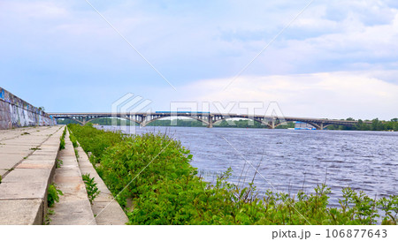 Stone river embankment overgrown with green bushes, metro bridge Stone river embankment overgrown with green bushes, metro bridge 106877643
