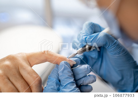 Nail care procedure in a beauty salon. Female hands and tools for manicure, process of performing manicure in beauty salon. Concept spa body care. Gloved hands of a skilled manicurist cutting cuticles 106877933