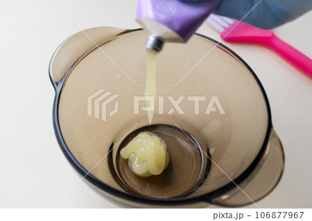 girl in blue rubber protective gloves holding a brush in her hands and stirring hair dye close-up colorist hair care at home hair mask.  106877967