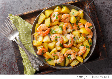 Spanish Potatoes roasted with Garlic Shrimp close-up in a plate. Horizontal top view Spanish Potatoes roasted with Garlic Shrimp close-up in a plate. Horizontal top view 106879381