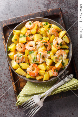 Roasted potatoes with garlic, herbs and shrimp close-up in a plate. Vertical top view Roasted potatoes with garlic, herbs and shrimp close-up in a plate. Vertical top view 106879384