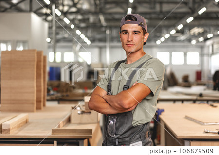 Portrait of young male carpenter standing in the wood workshop 106879509