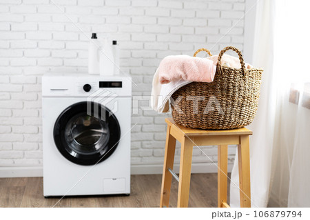 Laundry room with washing machine and basket with laundry 106879794