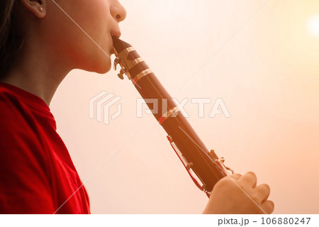 Young attractive girl playing clarinet, ebony in fall park Young attractive girl playing clarinet, ebony in fall park 106880247