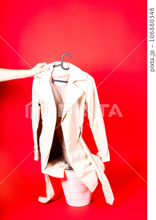 Shot of a young woman hand throwing her outwear dress in the trash isolated on red background 106880346