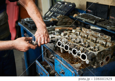 Close up of strong worker holding instrument, equipment by dirty hands. Hardworking male wearing uniform, working in garage, workshop, servicing center. Concept of manual labor. 106881929