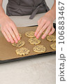 teenager boy's hands put raw american chocolate chip cookies on baking sheet. vertical shot of young chef hands making cookies 106883467