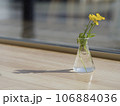 窓辺の小さなガラスの一輪挿しに黄色い花 106884036
