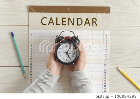 カレンダーの上で時計を持つ女の子の手。予定、スケジュール、計画、予約など	 106884595