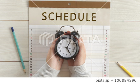 カレンダーの上で時計を持つ女の子の手。予定、スケジュール、計画、予約など	 カレンダーの上で時計を持つ女の子の手。予定、スケジュール、計画、予約など	 106884596