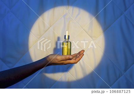 Soothing sleep: oil for sleep, melatonin and sweet dreams in a woman's hand on the background of a blanket at night 106887125