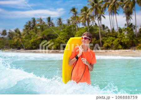 Child surfing on tropical beach. Surfer in ocean. 106888759
