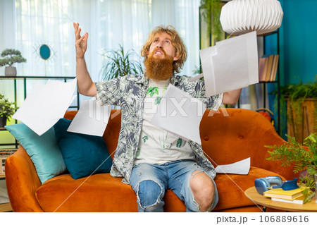 Stressed young man looking at unpaid bank debt loan, doing paperwork, planning budget, throws bills Stressed young man looking at unpaid bank debt loan, doing paperwork, planning budget, throws bills 106889616