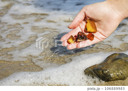 Beautiful pieces of amber in the hand of the sea background. A glowing wavy piece of amber in the palm of your hand. The sunstone. 106889983