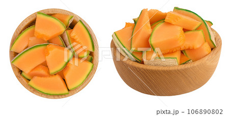 Cantaloupe melon pieces in wooden bowl isolated on white background with full depth of field. Top view. Flat lay Cantaloupe melon pieces in wooden bowl isolated on white background with full depth of field. Top view. Flat lay 106890802