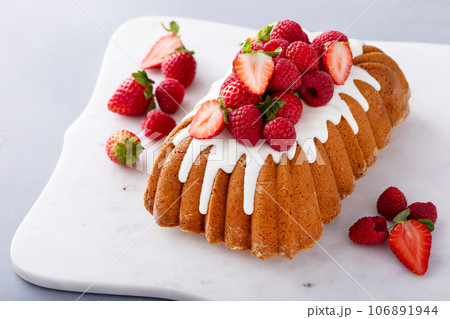 Traditional pound cake topped with glaze and fresh berries 106891944