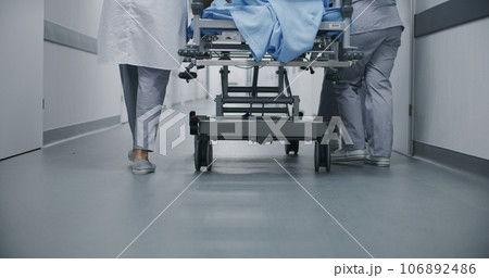 Doctors and paramedics move gurney with patient 106892486