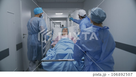 Doctors push stretcher with elderly woman 106892507